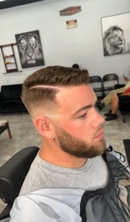 Client with a side-part comb-over, skin fade and full beard
