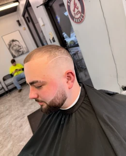 Client with a close buzz cut, skin fade, shaved design line and trimmed beard