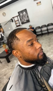 Client with a sharp hairline line-up, short taper and full beard